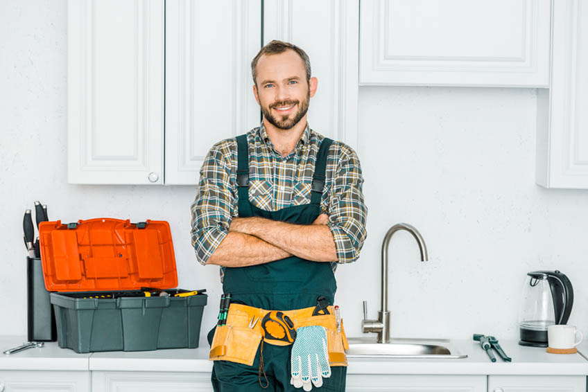 smiling plumber looking at camera in kitchen